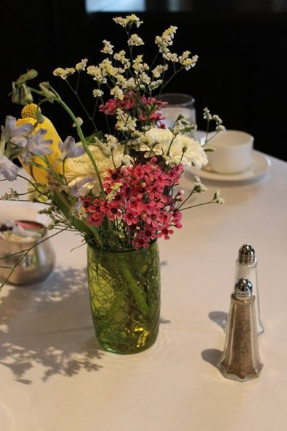 A colorful flower arrangement in a green vase on a dining table.