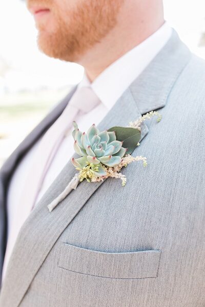 Close-up of a succulent boutonnière on a light grey suit jacket.