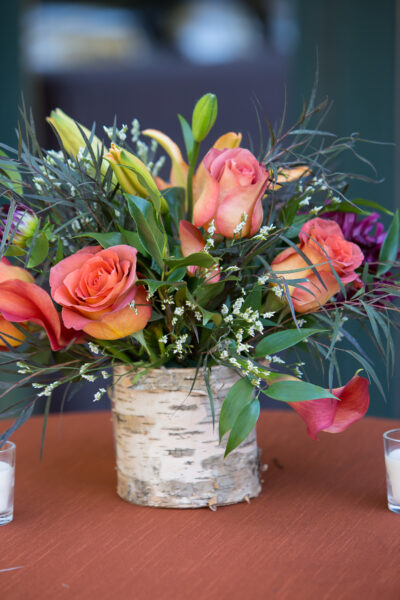 A vibrant bouquet of pink roses and greenery in a rustic vase.