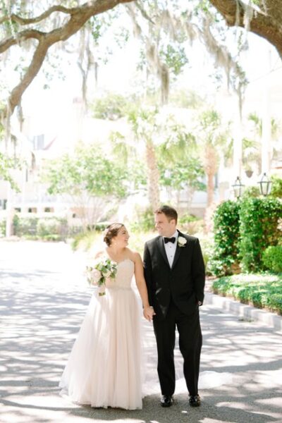 Bride and groom holding hands outdoors on wedding day.