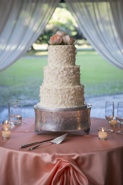 Elegant three-tier wedding cake with floral decorations on a rustic wooden stand.