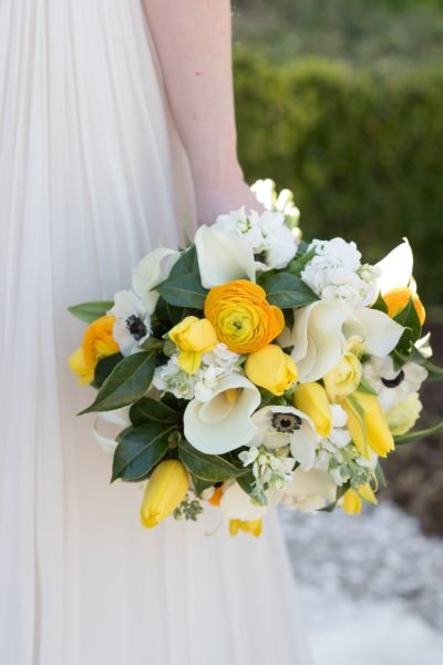 Bright yellow and white floral bouquet held by a bride.
