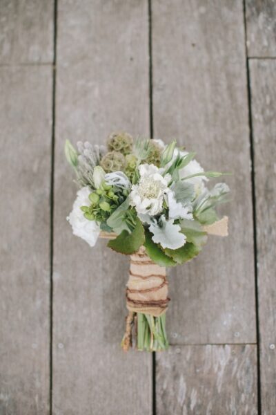 A delicate bouquet of white and green flowers wrapped with twine.