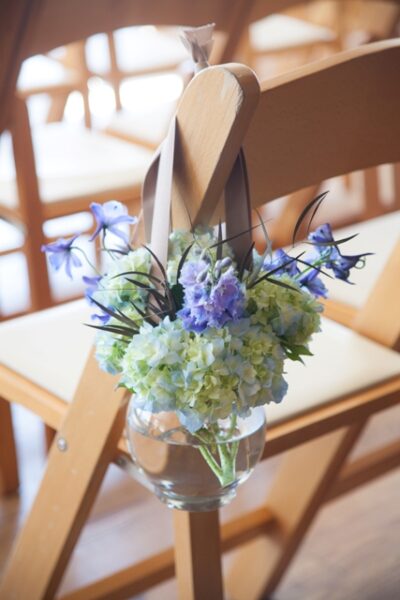 Elegant floral centerpiece with blue and white flowers on a wooden chair.
