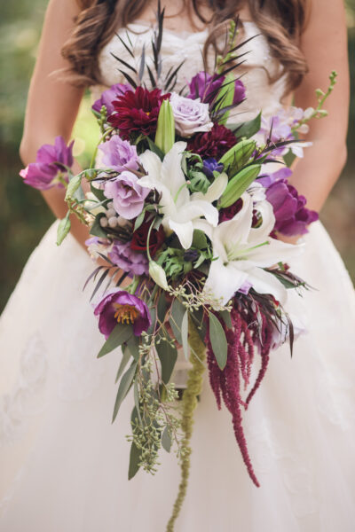 Elegant bridal bouquet with white lilies and purple flowers.