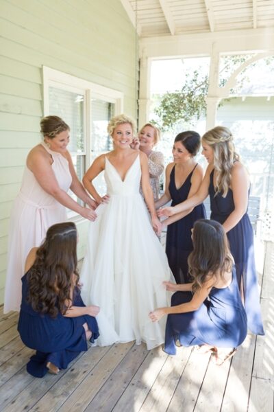 Bride getting ready with her bridesmaids in a sunlit room.