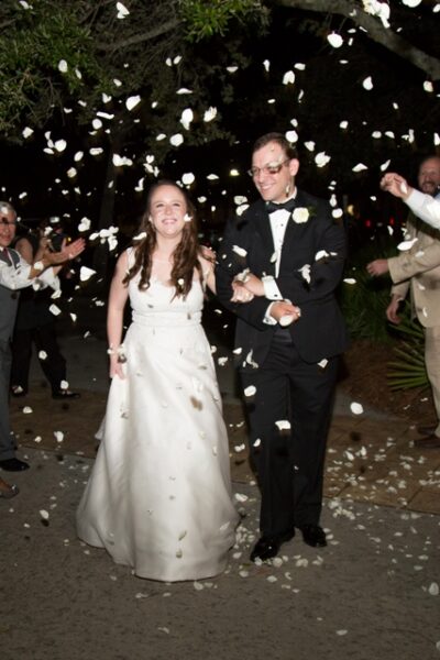 Newlywed couple joyfully walking through a celebratory shower of petals.