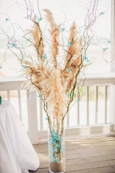 Decorative dried pampas grass arrangement in a glass vase on a windowsill.
