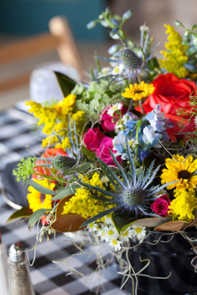 A vibrant bouquet featuring sunflowers, red and pink blooms, and greenery.