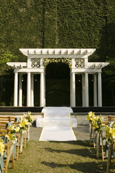 Elegant outdoor wedding altar with white columns and a decorated aisle.