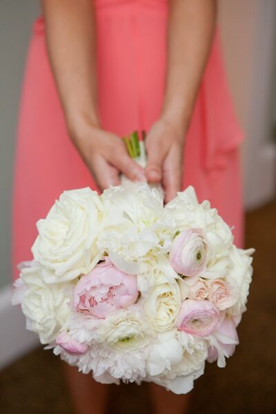 Hands holding a soft pink and white bridal bouquet.