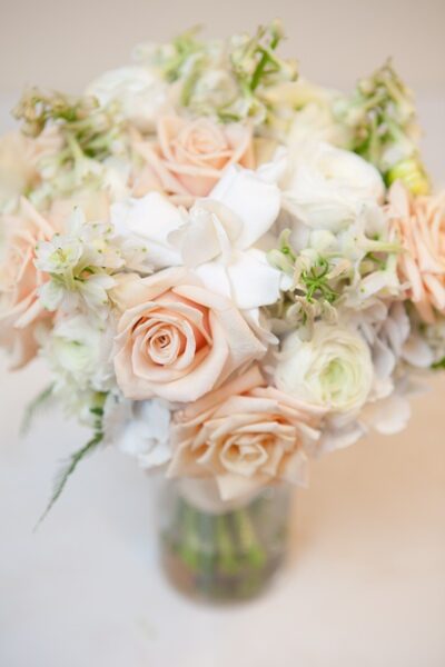 Elegant bouquet of soft peach and white roses with delicate greenery.
