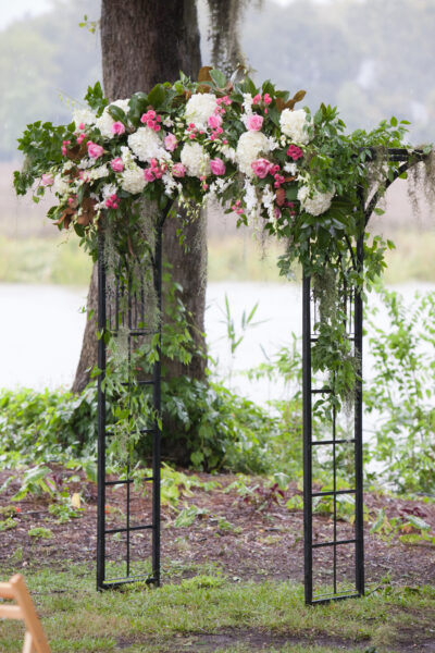 Elegant floral arch with pink and white flowers at an outdoor event.