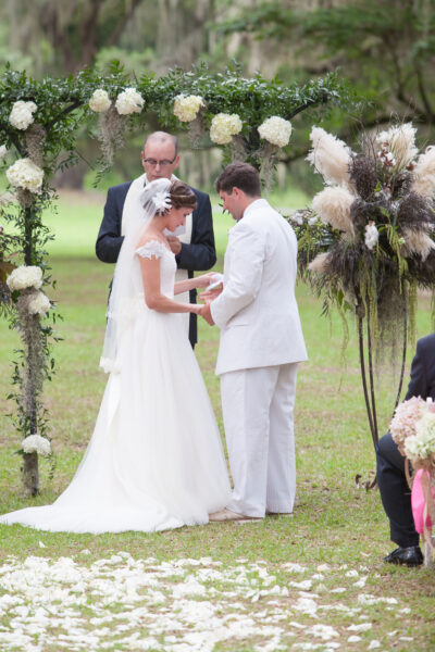Bride and groom exchanging vows outdoors during wedding ceremony.