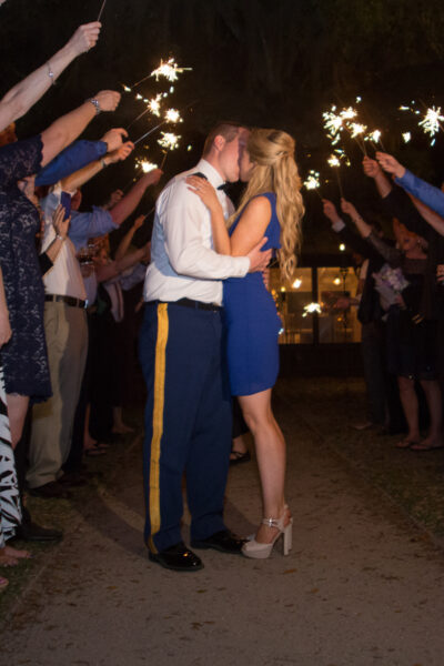 Couple shares a kiss amid sparklers at a nighttime celebration.