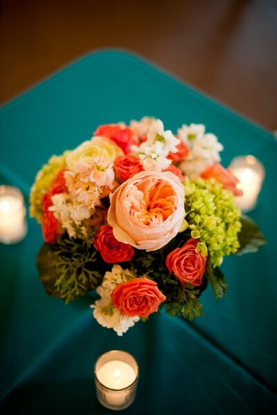 A vibrant bouquet with roses and hydrangeas on a teal tablecloth.