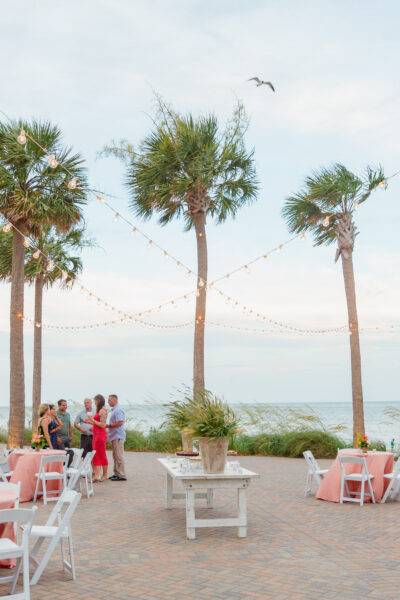 Outdoor wedding reception by the beach with palm trees and soft lighting.