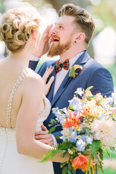 Bride whispering to groom during outdoor wedding.