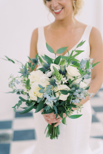 Bride holding a lush bouquet of white flowers and greenery.