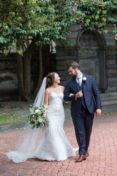 Bride and groom walking arm in arm outdoors on their wedding day.