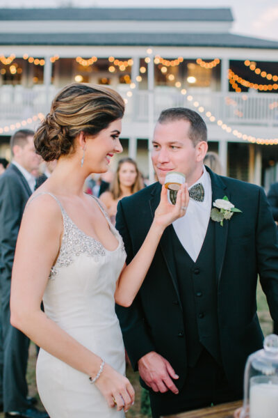 Bride playfully feeding groom a bite during wedding reception.