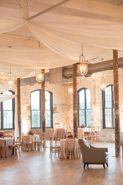 Elegant event space with draped ceilings and wooden beams.