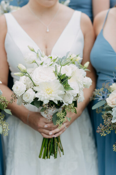 Bridesmaids holding elegant white floral bouquets at a wedding.