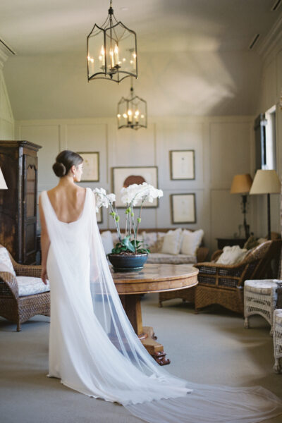 Bride in an elegant white dress standing in a cozy, stylish living room.