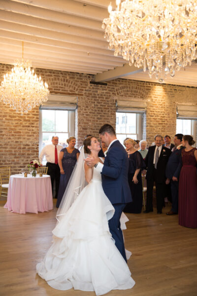 Bride and groom share their first dance in a warmly lit reception hall.