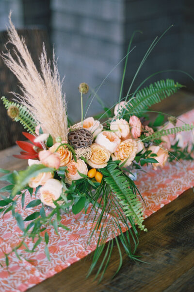 Elegant floral arrangement with peach roses and greenery on a wooden table.