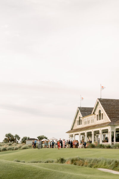Golfers walking near a clubhouse on a cloudy day.