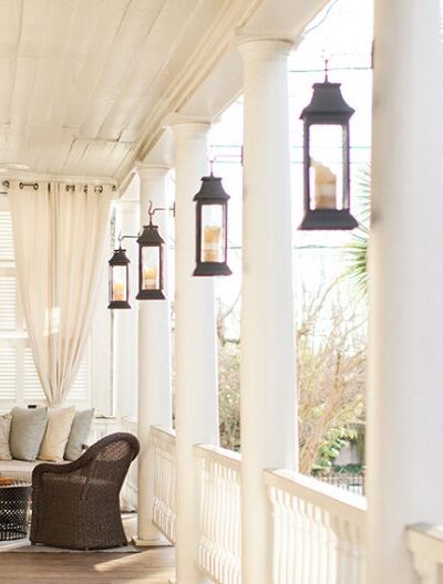 A bright porch with hanging lanterns and wicker furniture.