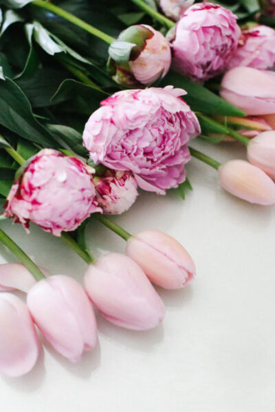 A bouquet of pink peonies and tulips on a white surface.