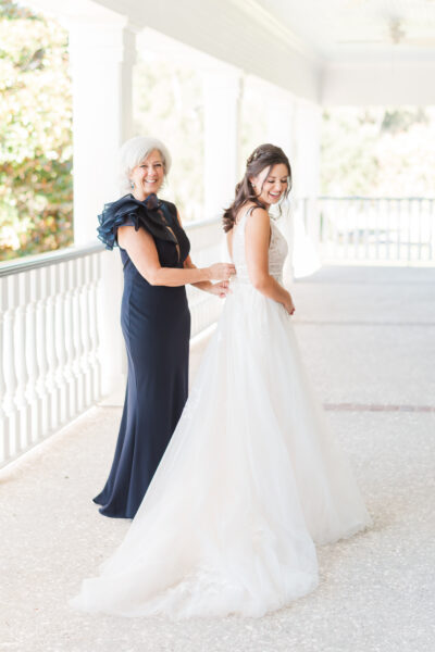 Bride and woman in elegant black dress share a joyful moment.