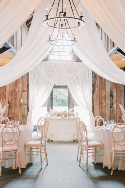 Elegant wedding reception setup with white drapes and chandeliers.