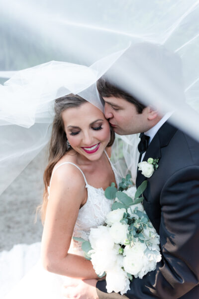 Bride and groom share a tender moment under the veil on their wedding day.