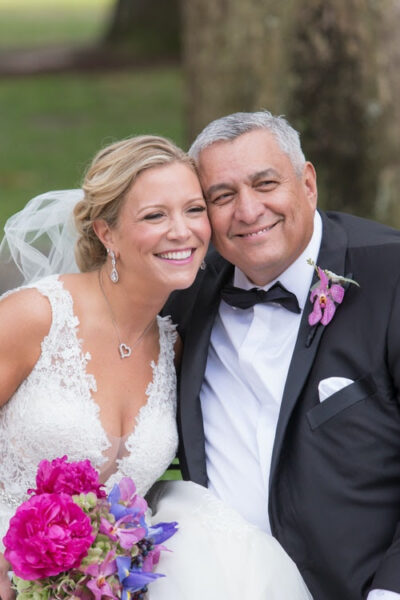 Smiling bride and groom posing happily outdoors on their wedding day.