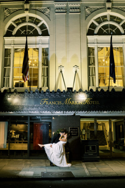 Person walking in front of a lit-up historic building at night.