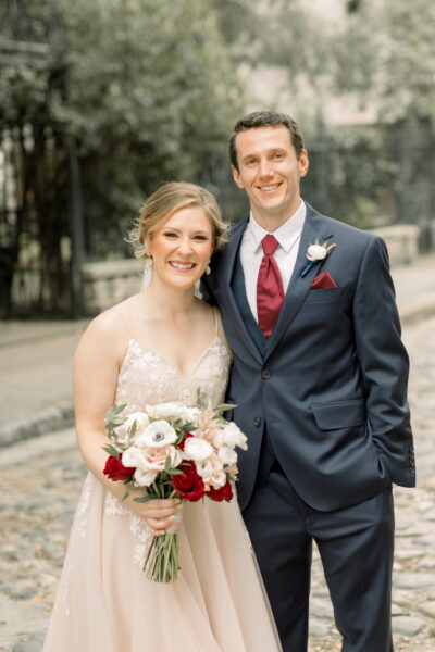 A happy bride and groom posing outdoors on their wedding day.