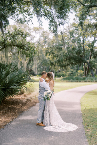 Couple embraces tenderly on a winding garden path surrounded by lush greenery.
