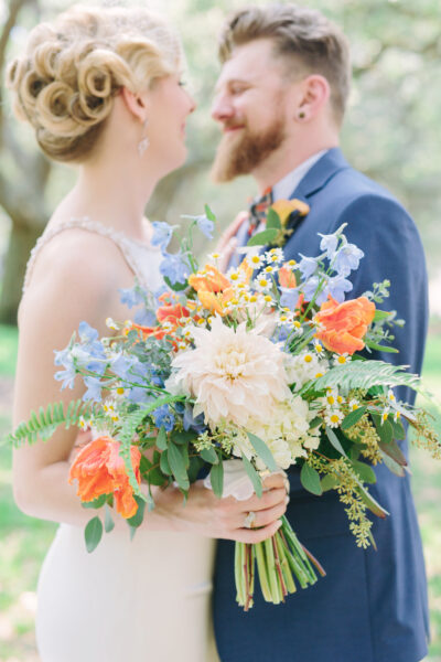 Bride and groom holding a colorful bouquet during their wedding.