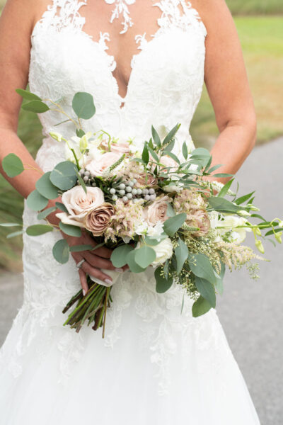 Bride holding a beautiful bouquet of mixed flowers and greenery.