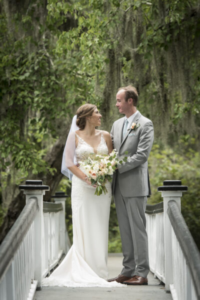 Bride and groom smiling at each other outdoors on their wedding day.