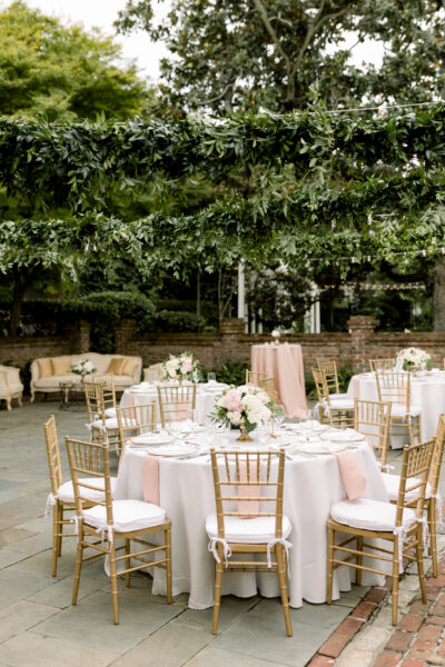Elegant outdoor wedding reception with floral decorations and round tables.