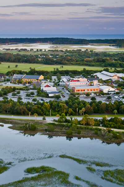 Aerial view of a coastal town with buildings and water bodies at sunset.