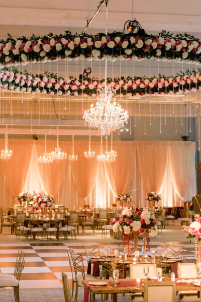 Elegant wedding venue with floral chandeliers and warm lighting.