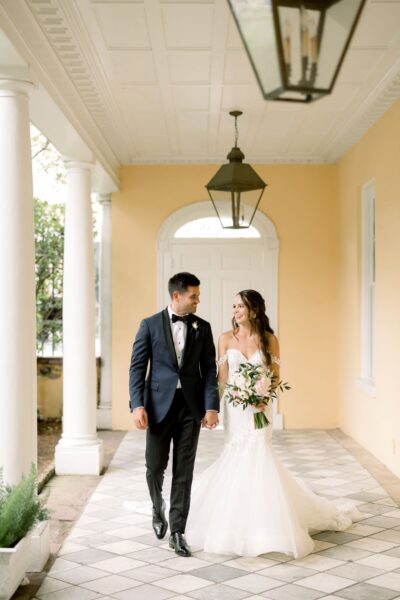 Bride and groom holding hands in a charming corridor.
