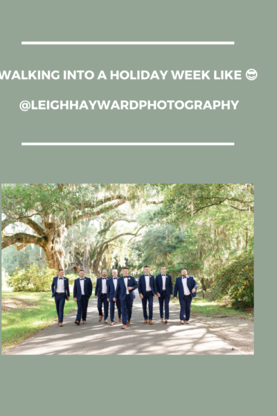 A group of people in formal attire walking under sunlit trees.