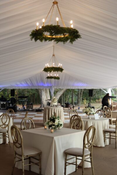 Elegant wedding reception setup with white drapery and chandeliers.