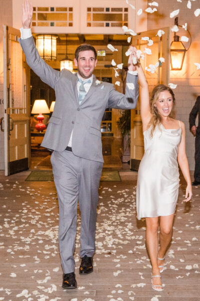 A joyful couple walks through falling confetti at their celebration.